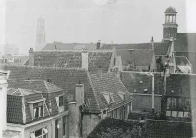 876896 Gezicht over de daken van panden aan de Oudegracht op de St.-Augustinuskerk (rechts, Oudegracht 69) te Utrecht, ...